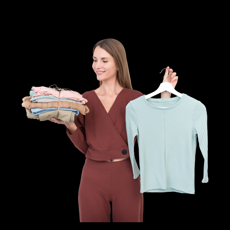 Frau hält einen Stapel Kleidung in der einen und ein Oberteil in der anderen Hand.