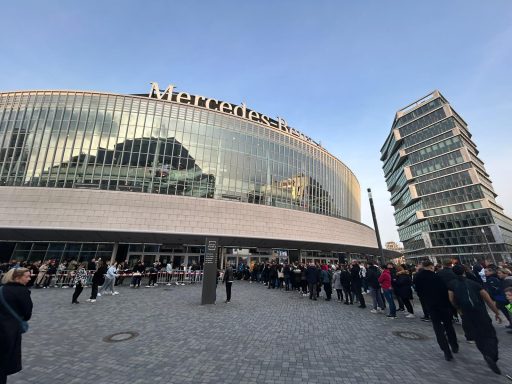 Modernes Gebäude mit Glasfassade und vielen Menschen vor dem Eingang.